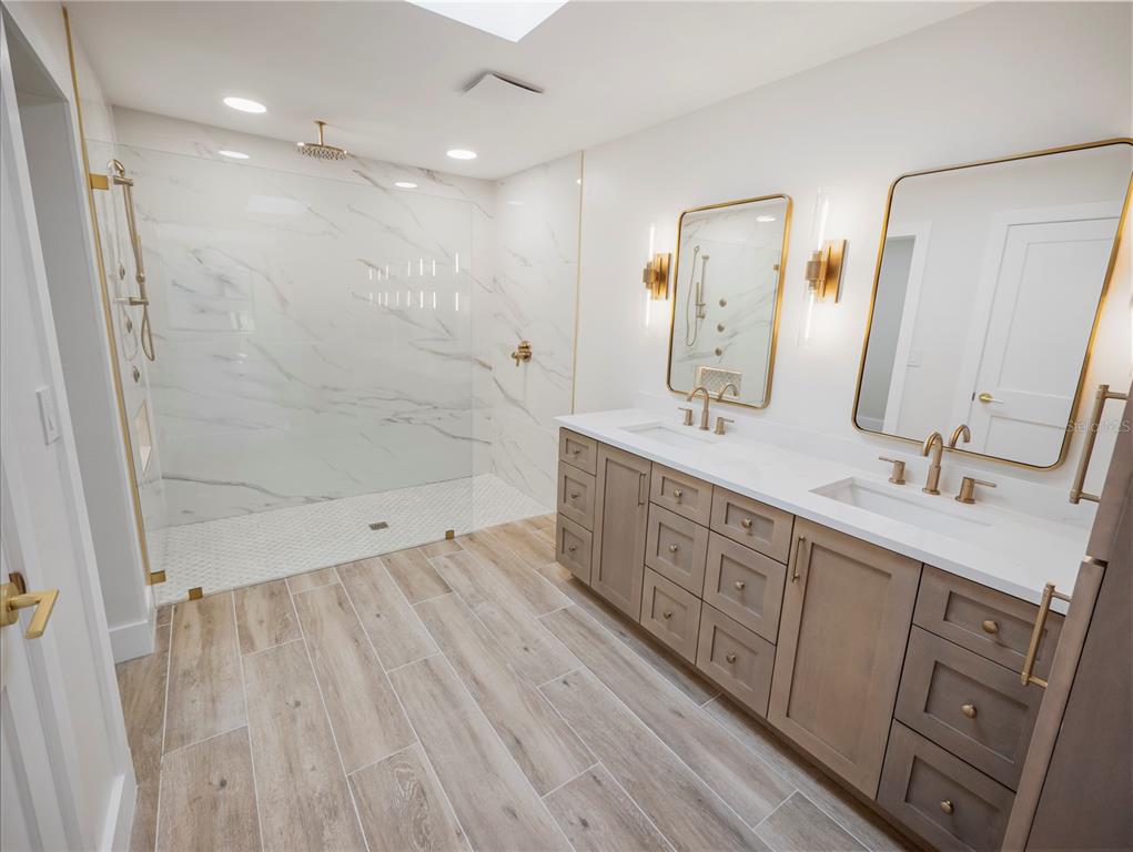 6790 Edgeworth Drive Orlando, FL 32819 - Photo 21 of 57 a spacious bathroom with double vanity sink a mirror and shower