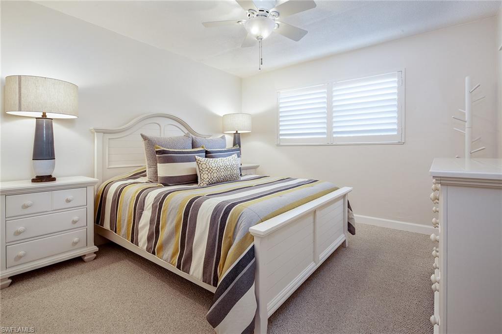 72 7th Street South, Unit 208 Naples, FL 34102 - Photo 7 of 10 a bedroom with bed and a night stand on a dresser