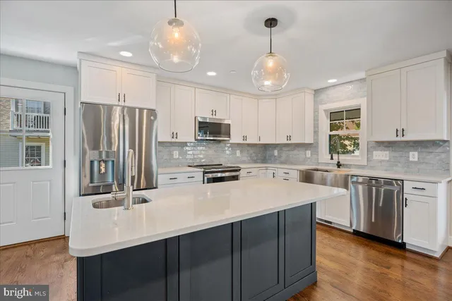 a large kitchen with stainless steel appliances kitchen island granite countertop a sink dishwasher a stove and a refrigerator with wooden floor