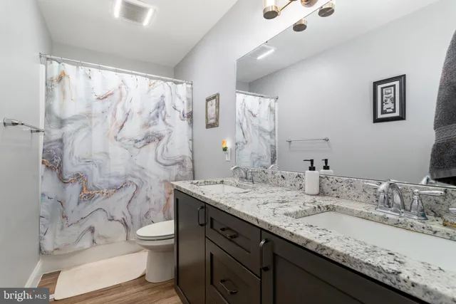 a bathroom with a granite countertop sink toilet and shower