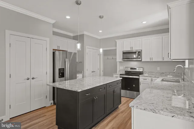 a kitchen with kitchen island granite countertop stainless steel appliances sink stove microwave and cabinets