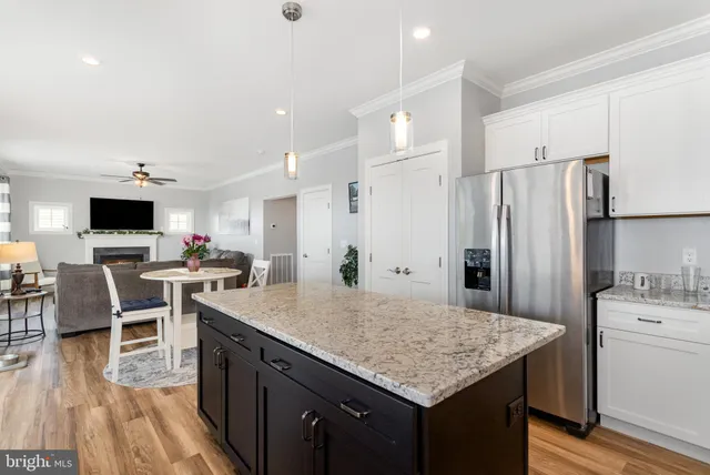 a kitchen with stainless steel appliances kitchen island granite countertop a table chairs stove and refrigerator