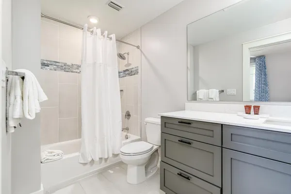 a spacious bedroom with a bed and a flat tv screen on dresser