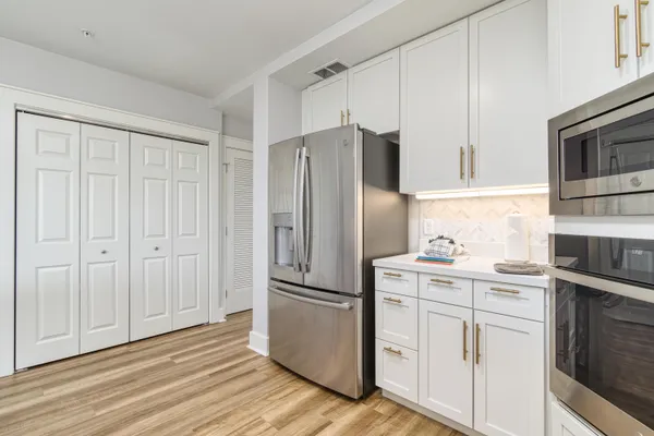 a kitchen with cabinets stainless steel appliances and wooden floor