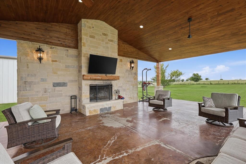 430 Ridgecrest Place Sanger, TX 76266 - Photo 32 of 40 Expansive covered patio featuring a stone fireplace with a wood mantel, a wood-paneled vaulted ceiling with recessed lighting and ceiling fans, and a stained concrete floor