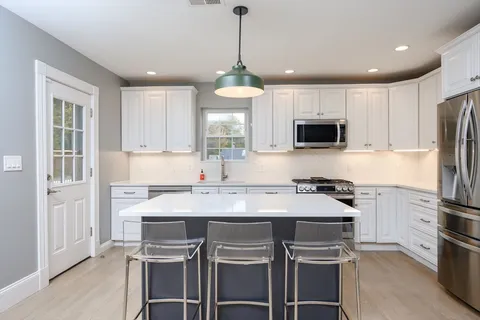 a kitchen with kitchen island white cabinets and stainless steel appliances