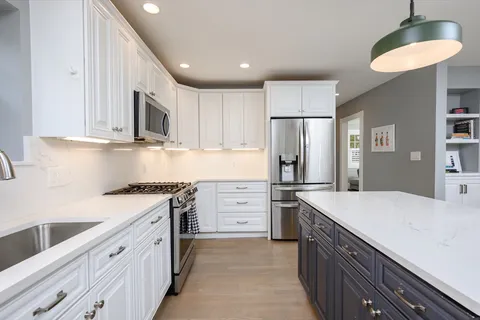 a kitchen with granite countertop a sink stove refrigerator and cabinets