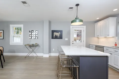 a dining room with wooden floor a chandelier a wooden table and chairs