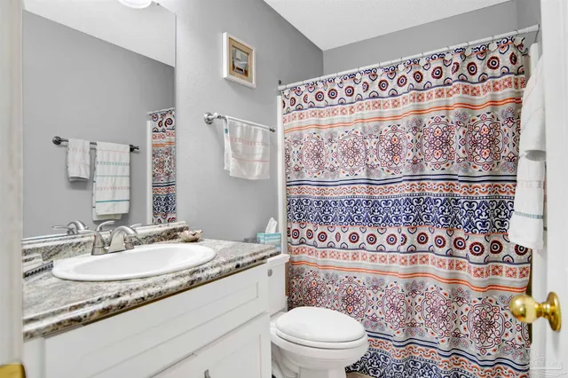 a bathroom with a granite countertop sink mirror vanity and toilet
