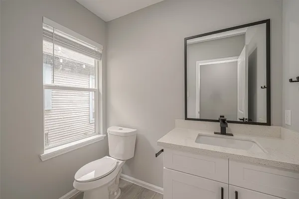 a bathroom with a toilet a sink a mirror and window