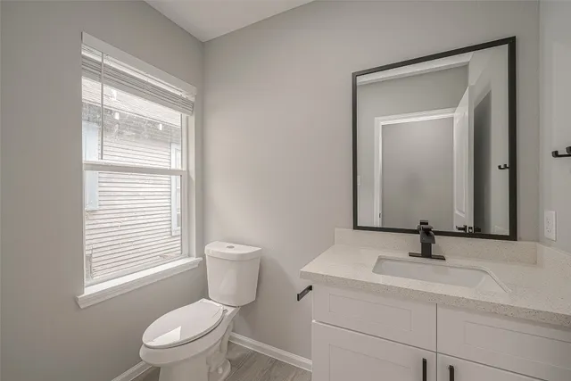 a bathroom with a toilet a sink a mirror and window