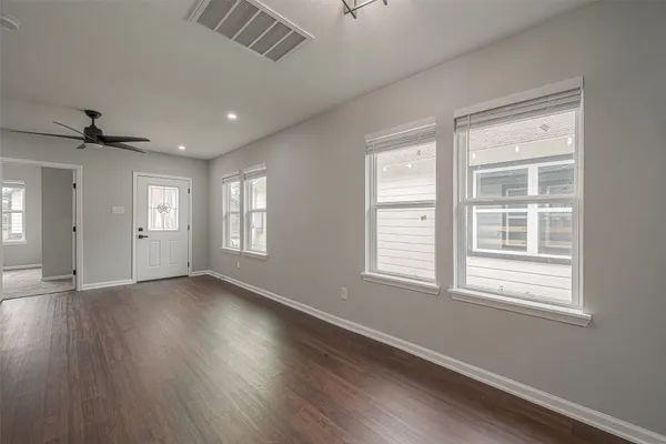 a view of an empty room with wooden floor and a window