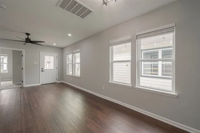 a view of an empty room with wooden floor and a window