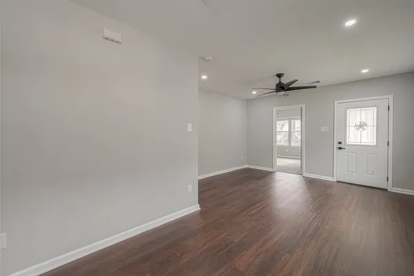 a view of an empty room with a window and wooden floor