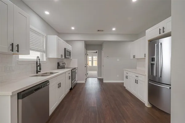 a large kitchen with a center island wooden floor stainless steel appliances and windows