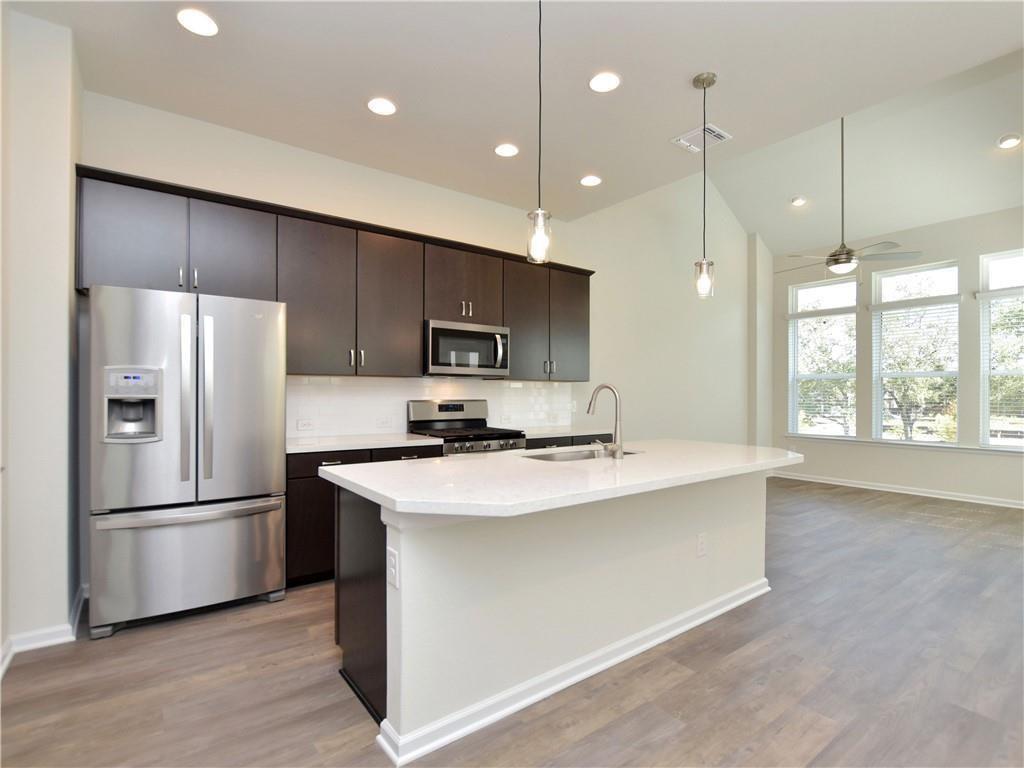 13611 Terrett Trace, Unit 108 Austin, TX 78717 - Photo 11 of 33 a kitchen with stainless steel appliances a refrigerator sink and wooden floor