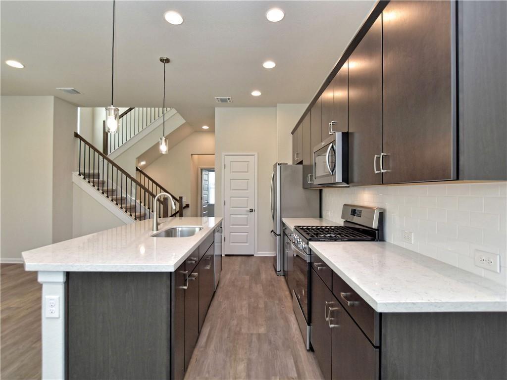 13611 Terrett Trace, Unit 108 Austin, TX 78717 - Photo 13 of 33 a kitchen with stainless steel appliances granite countertop a sink a stove and a wooden floors