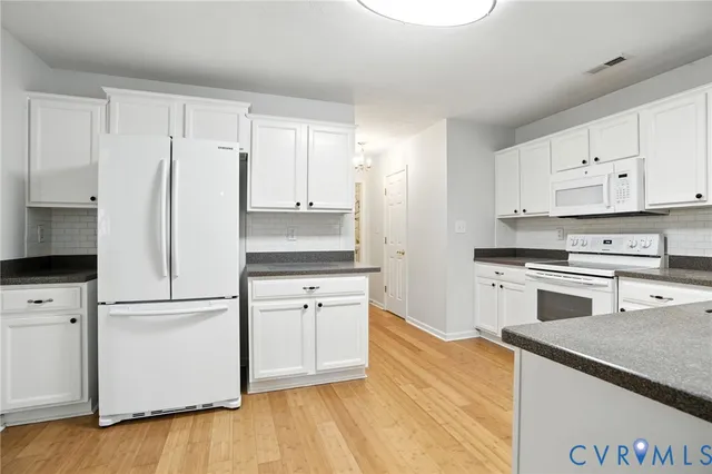 a kitchen with granite countertop white cabinets and white appliances