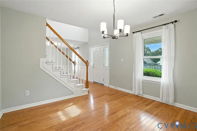 a view of a livingroom with wooden floor staircase and a chandelier