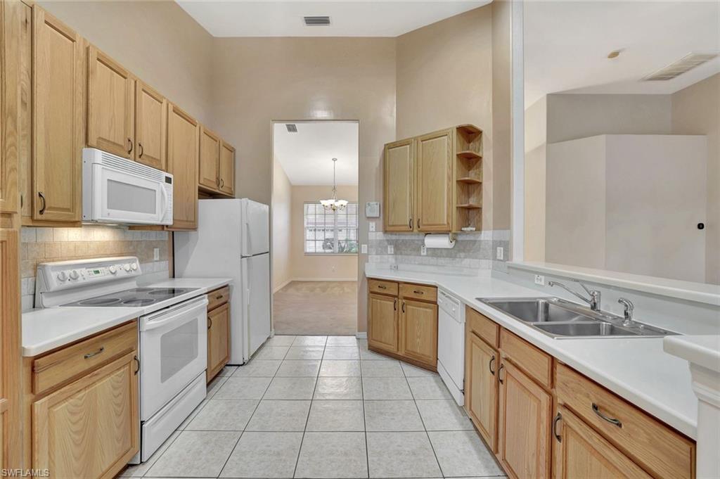 3617 Recreation Lane Naples, FL 34116 - Photo 7 of 25 a large kitchen with stainless steel appliances granite countertop a sink and dishwasher a stove top oven with wooden floor