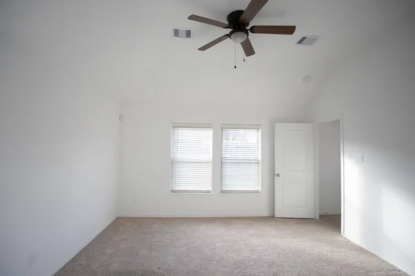an empty room with windows and fan