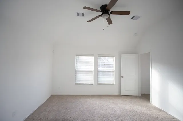 an empty room with windows and fan