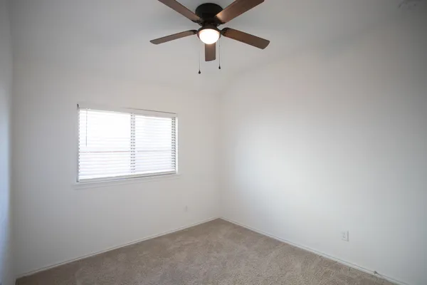 an empty room with a window and a fan