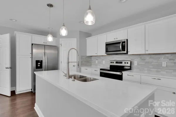 a kitchen with stainless steel appliances a sink a stove a refrigerator a center island and cabinets