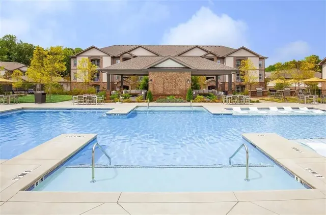 a view of a white house with a swimming pool and a lawn chairs under an umbrella