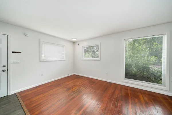 an empty room with wooden floor and windows