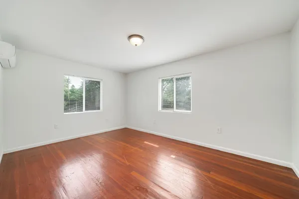 an empty room with wooden floor and windows