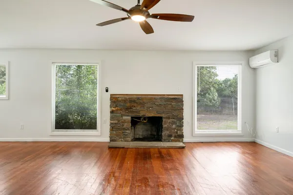 an empty room with wooden floor fireplace and windows