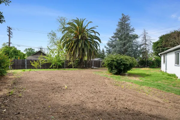 a view of a house with a big yard plants and large trees