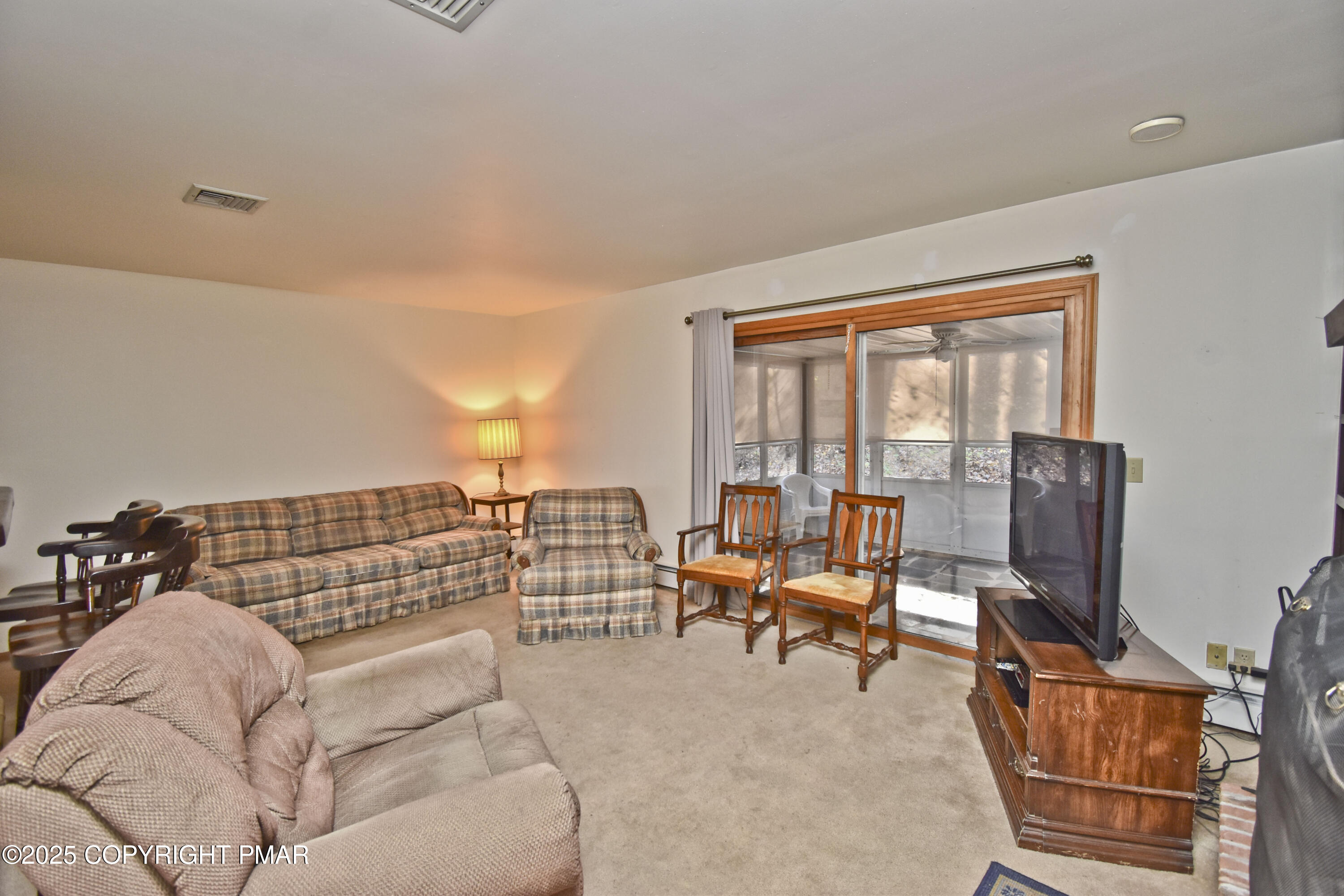 5294 Cherry Valley Road Saylorsburg, PA 18353 - Photo 12 of 53 a living room with furniture a lamp and a floor to ceiling window