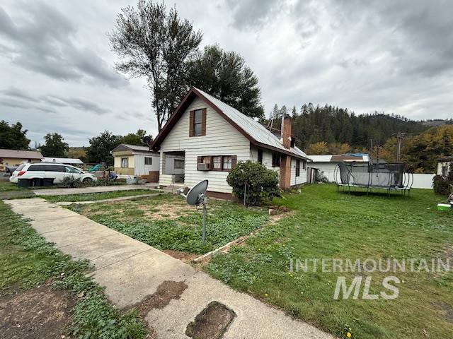 204 Front Street Kooskia, ID 83539 - Photo 3 of 25 View of property exterior featuring a trampoline, a lawn, and a chimney