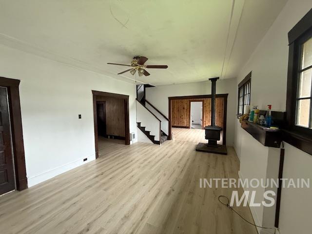 204 Front Street Kooskia, ID 83539 - Photo 7 of 25 Unfurnished living room with a wood stove, light wood-style floors, stairs, and ceiling fan