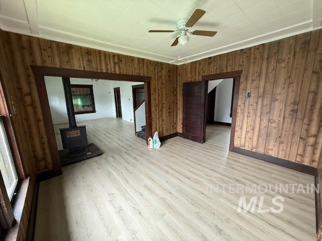 204 Front Street Kooskia, ID 83539 - Photo 9 of 25 Unfurnished living room featuring wood walls, a wood stove, stairs, wood finished floors, and ceiling fan