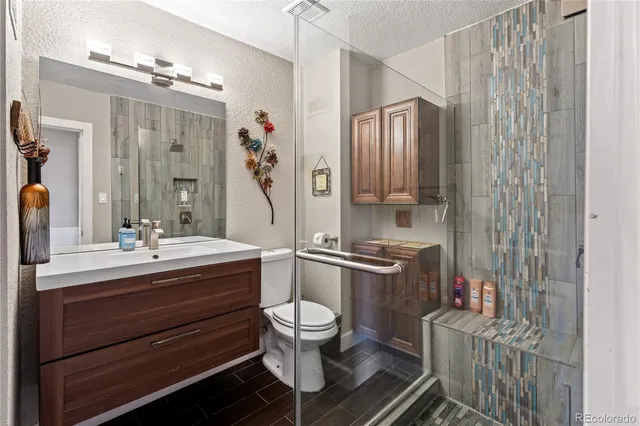 a bathroom with a double vanity sink toilet mirror and shower