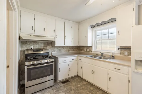 a kitchen with granite countertop white cabinets and appliances