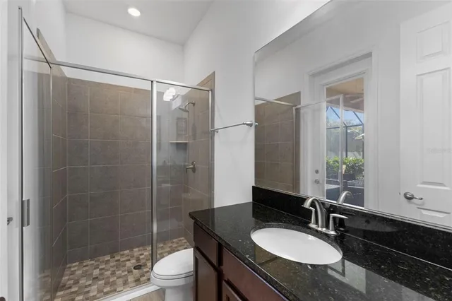 a bathroom with a granite countertop sink toilet a mirror and shower