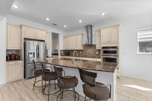 a kitchen with stainless steel appliances granite countertop a stove a refrigerator a sink a dining table and chairs with wooden floor