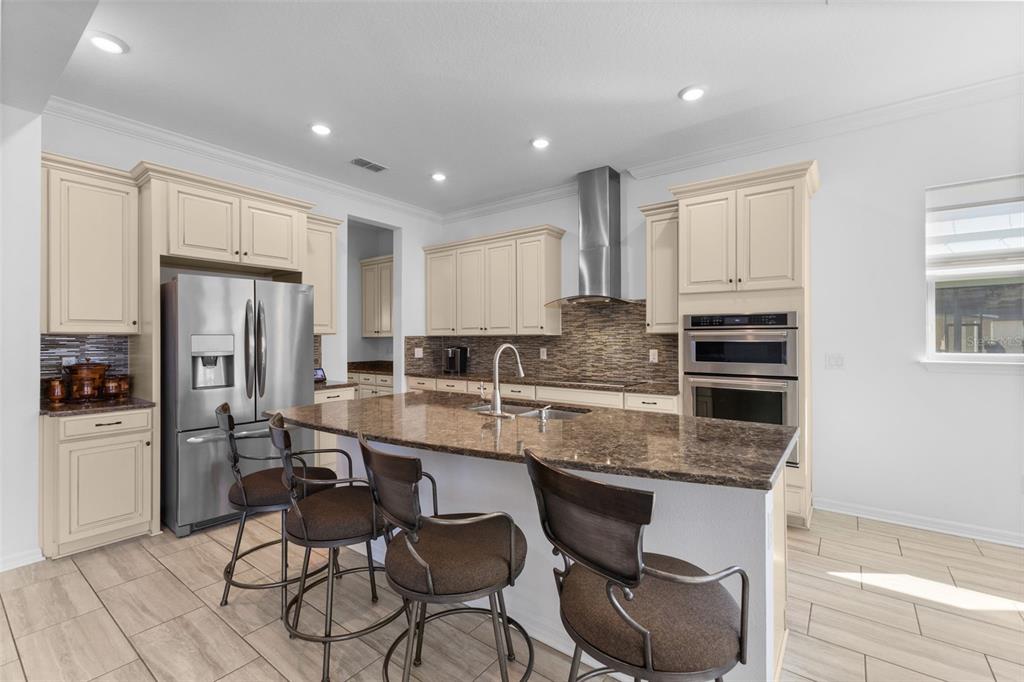 13065 Bliss Loop Bradenton, FL 34211 - Photo 7 of 54 a kitchen with stainless steel appliances granite countertop a stove a refrigerator a sink a dining table and chairs with wooden floor