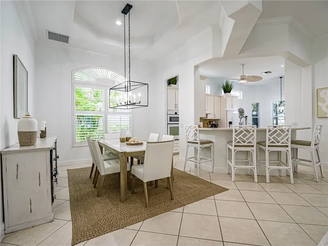 a dining room with furniture a chandelier and kitchen view