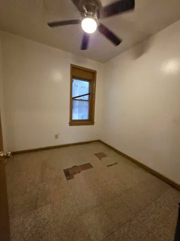 an empty room with a ceiling fan and a window
