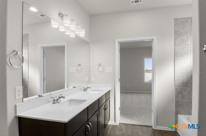 2431 Winding Creek Road Kyle, TX 78640 - Photo 11 of 29 a bathroom with a sink double vanity and a mirror
