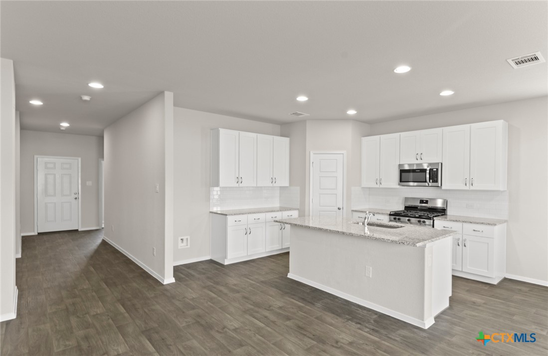 2431 Winding Creek Road Kyle, TX 78640 - Photo 3 of 29 a kitchen with white cabinets and appliances