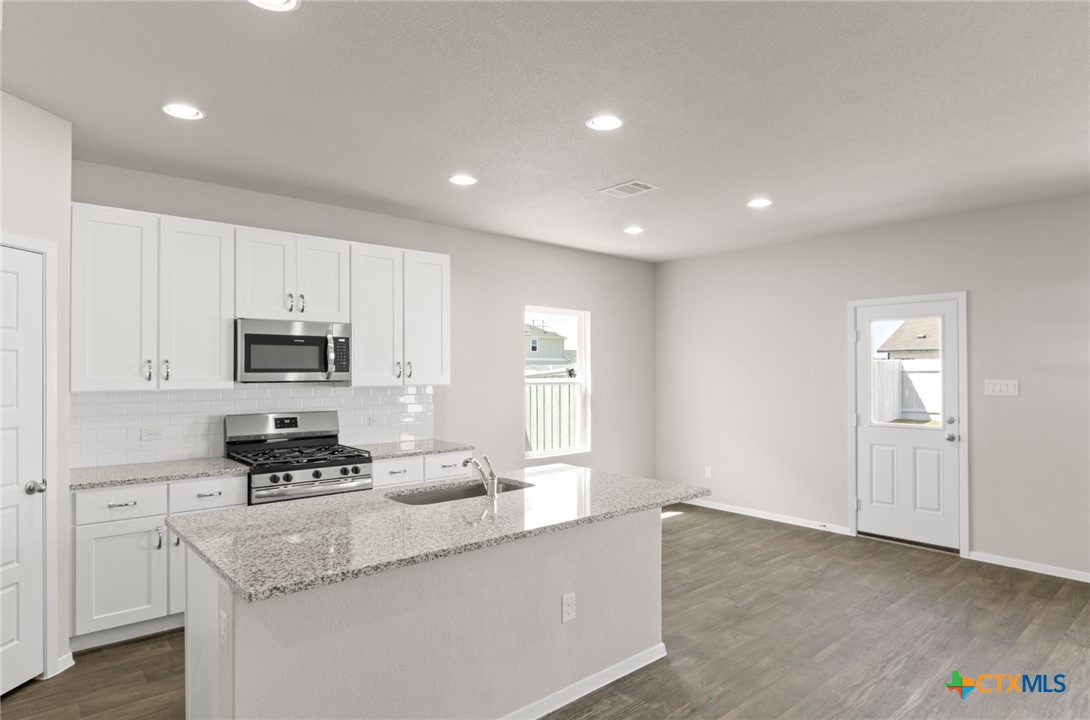 2431 Winding Creek Road Kyle, TX 78640 - Photo 4 of 29 a kitchen with granite countertop a stove a sink and a refrigerator