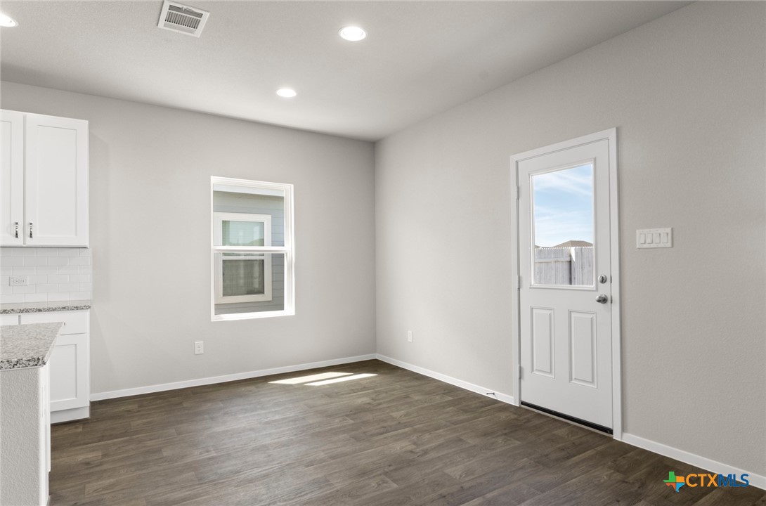 2431 Winding Creek Road Kyle, TX 78640 - Photo 5 of 29 an empty room with wooden floor and windows