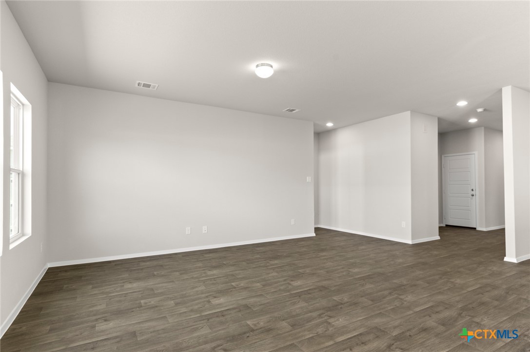 2431 Winding Creek Road Kyle, TX 78640 - Photo 6 of 29 a view of an empty room with wooden floor and a window