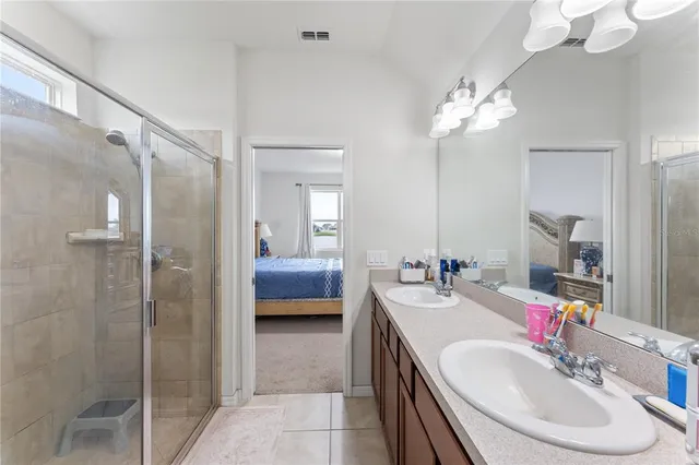a en suite bathroom with a double vanity sink a mirror and a shower